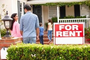 An image of a family walking into a house with a for rent sign in front of it